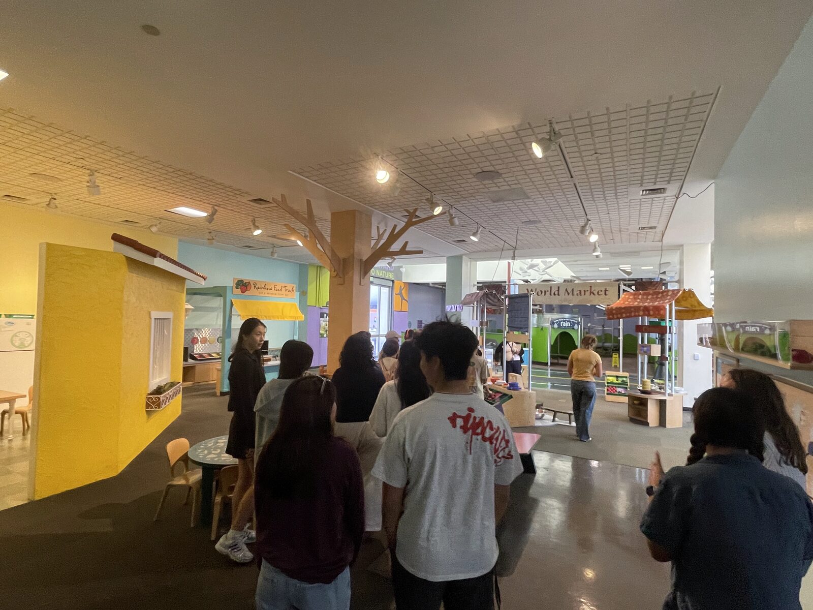 Students walking through the colorful World Market and Rainbow Food Truck play areas at CDM